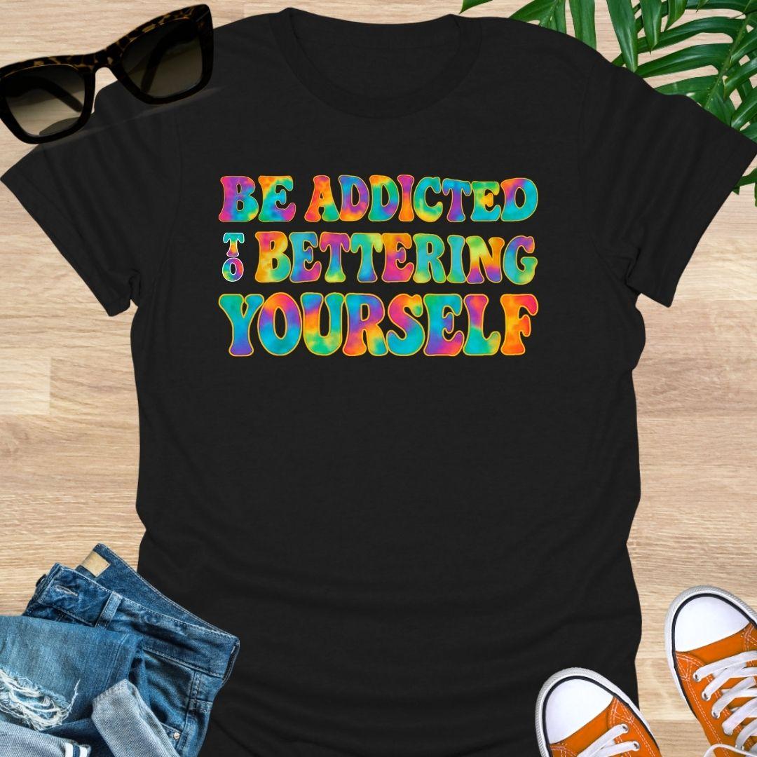 Rainbow tie-dye “Be Addicted to Bettering Yourself” text on black unisex growth-mindset tee.