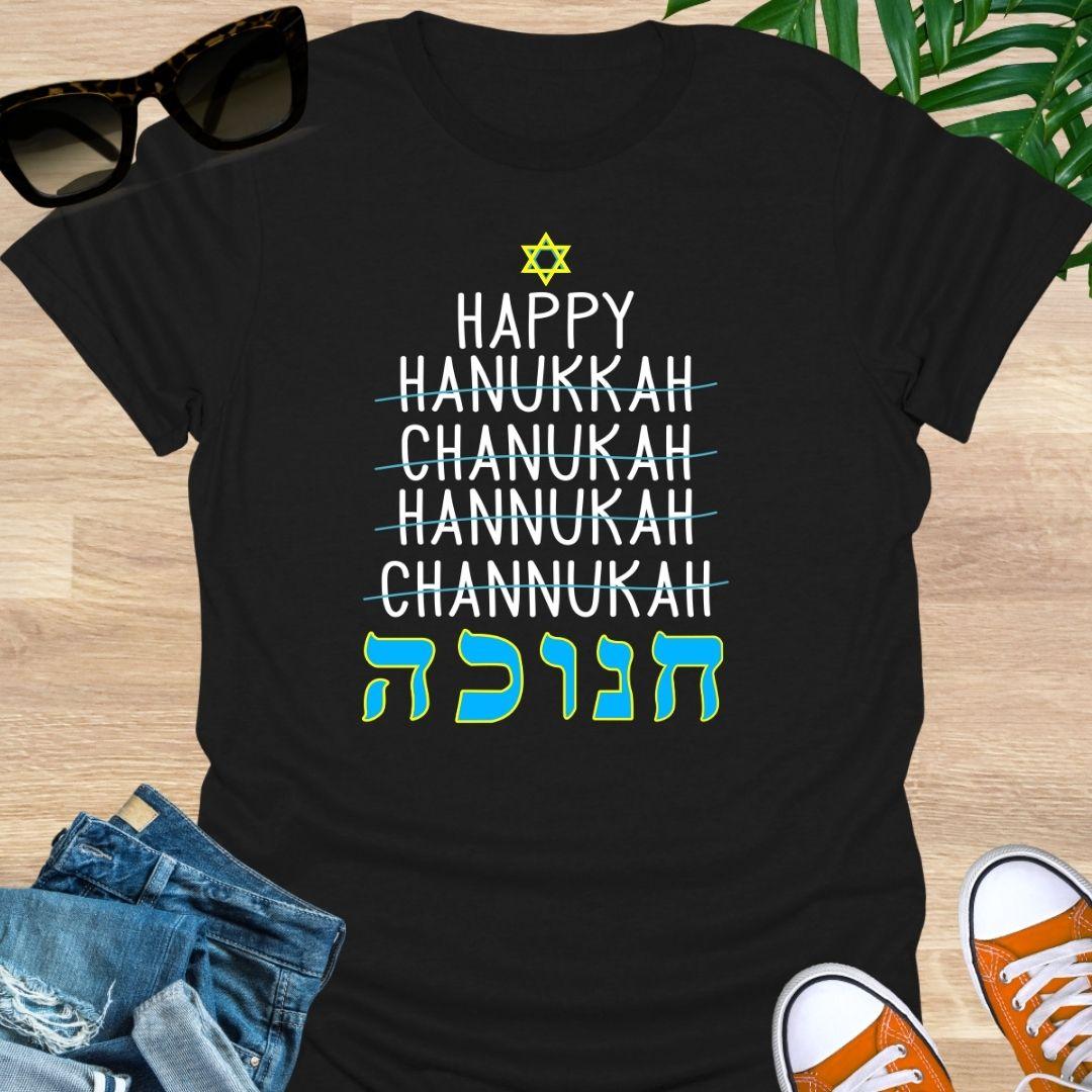 Happy Hanukkah with crossed-out spellings and large Hebrew letters plus a Star of David on a black unisex tee.
