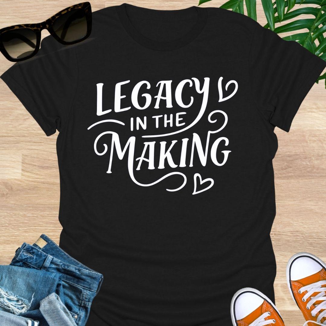 White script “Legacy in the Making” with heart flourishes on a black motivational graphic tee.