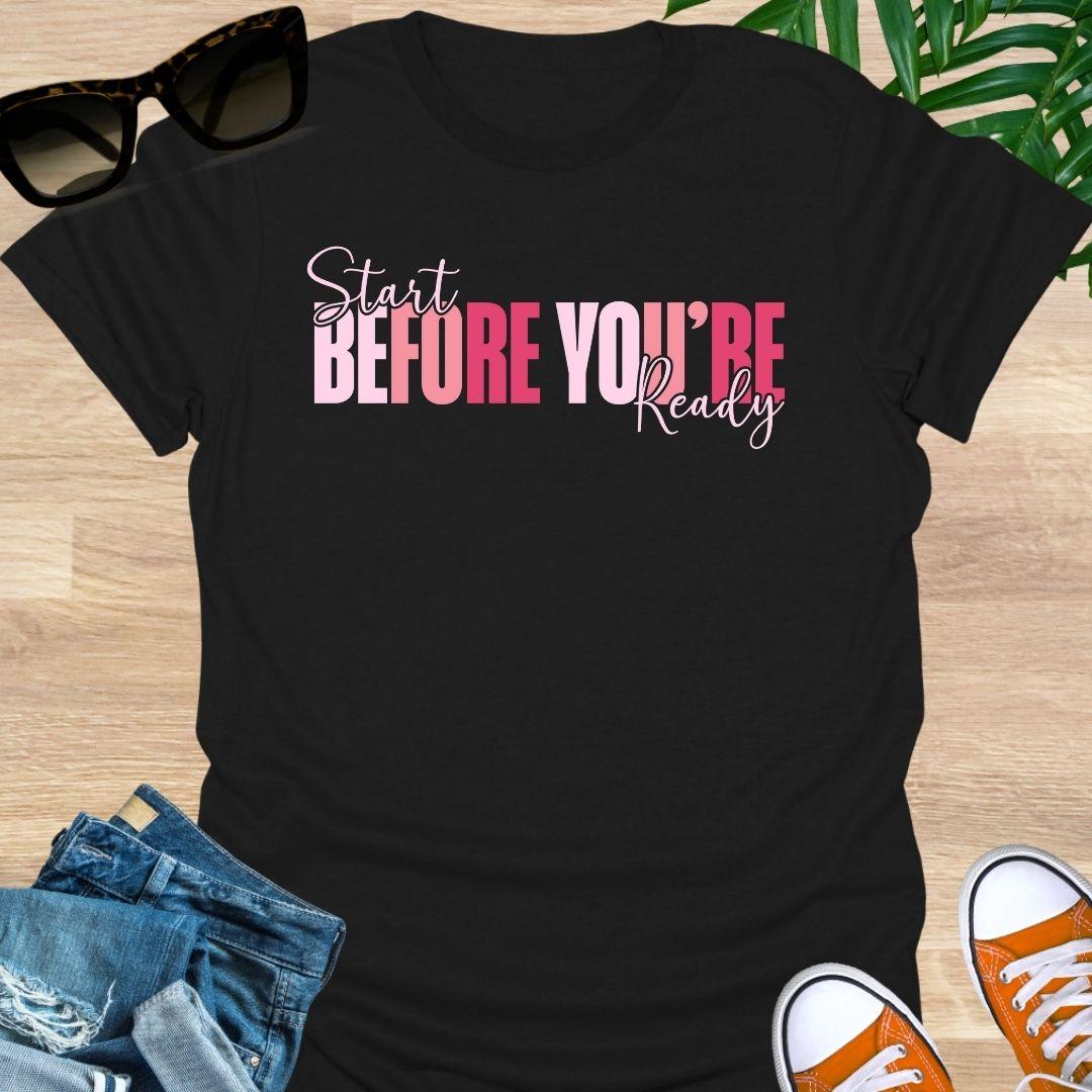 “Start Before You’re Ready” in pink gradient block letters with script overlay on a black unisex tee.