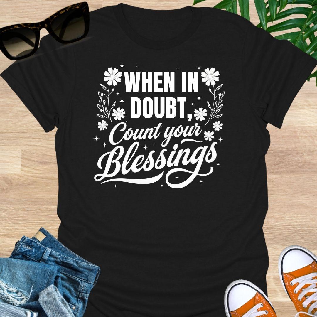 “When in Doubt, Count Your Blessings” in white script with floral and sparkle accents on a black unisex tee.