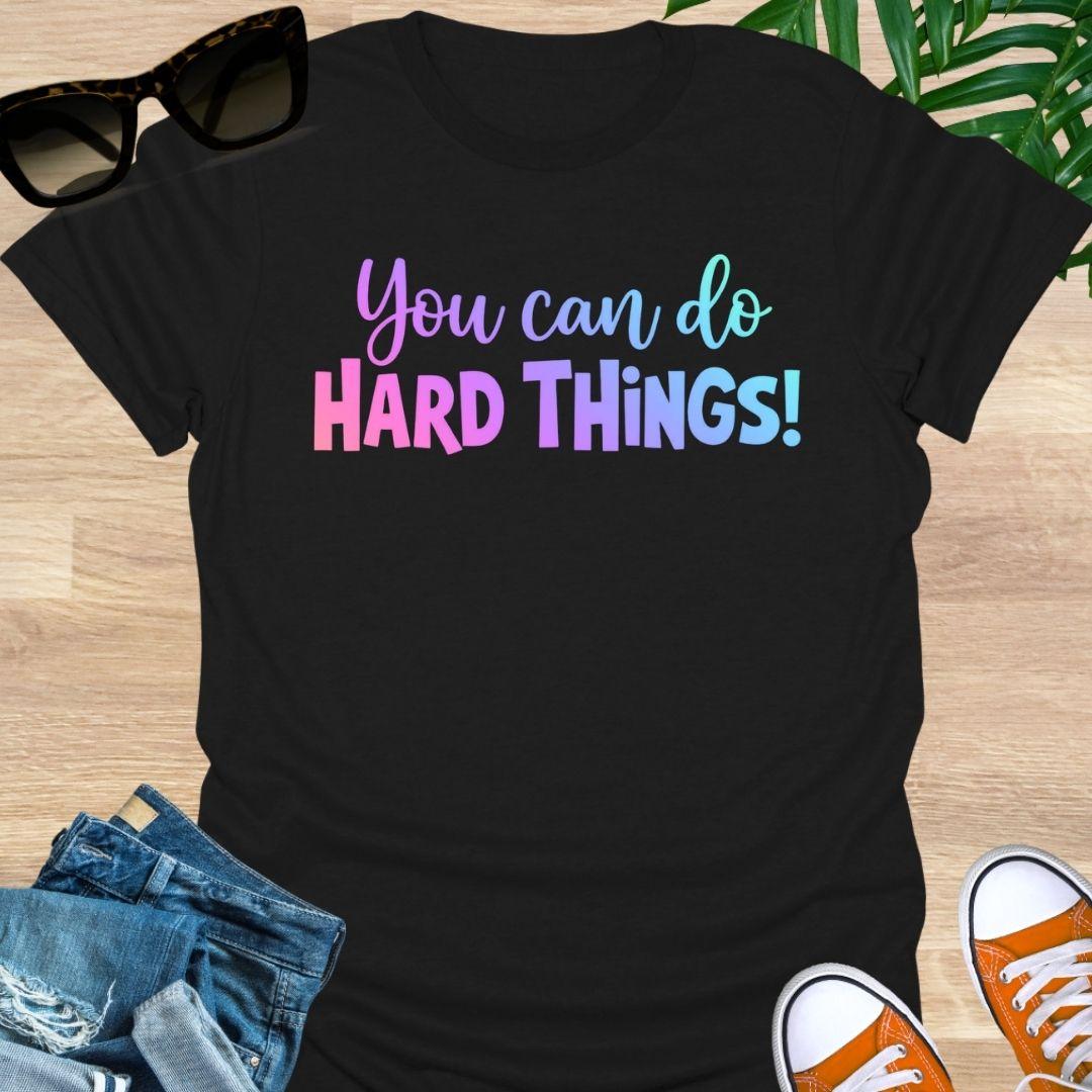 “You Can Do Hard Things” in sunrise gradient lettering on a black unisex tee.