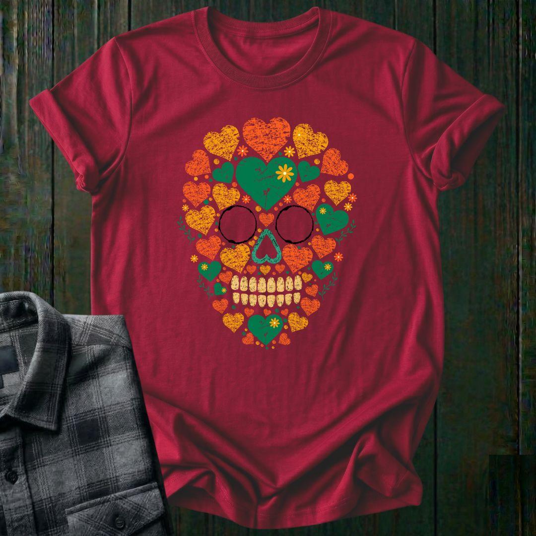 Distressed floral skull graphic made from colorful hearts, flowers, and botanical elements in green, orange, and yellow vintage-style artwork on a red tee
