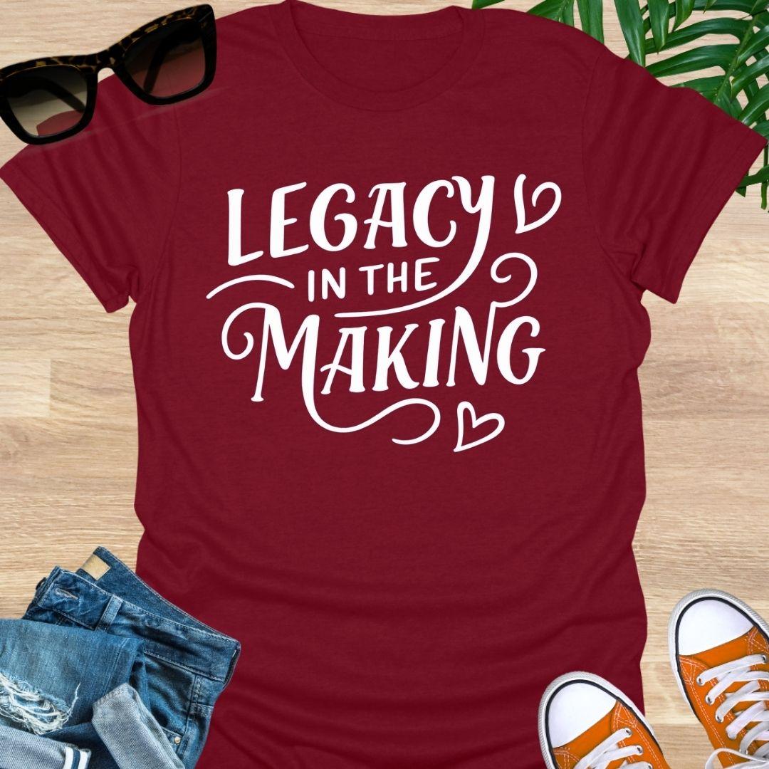 White script “Legacy in the Making” with heart flourishes on a red motivational graphic tee.
