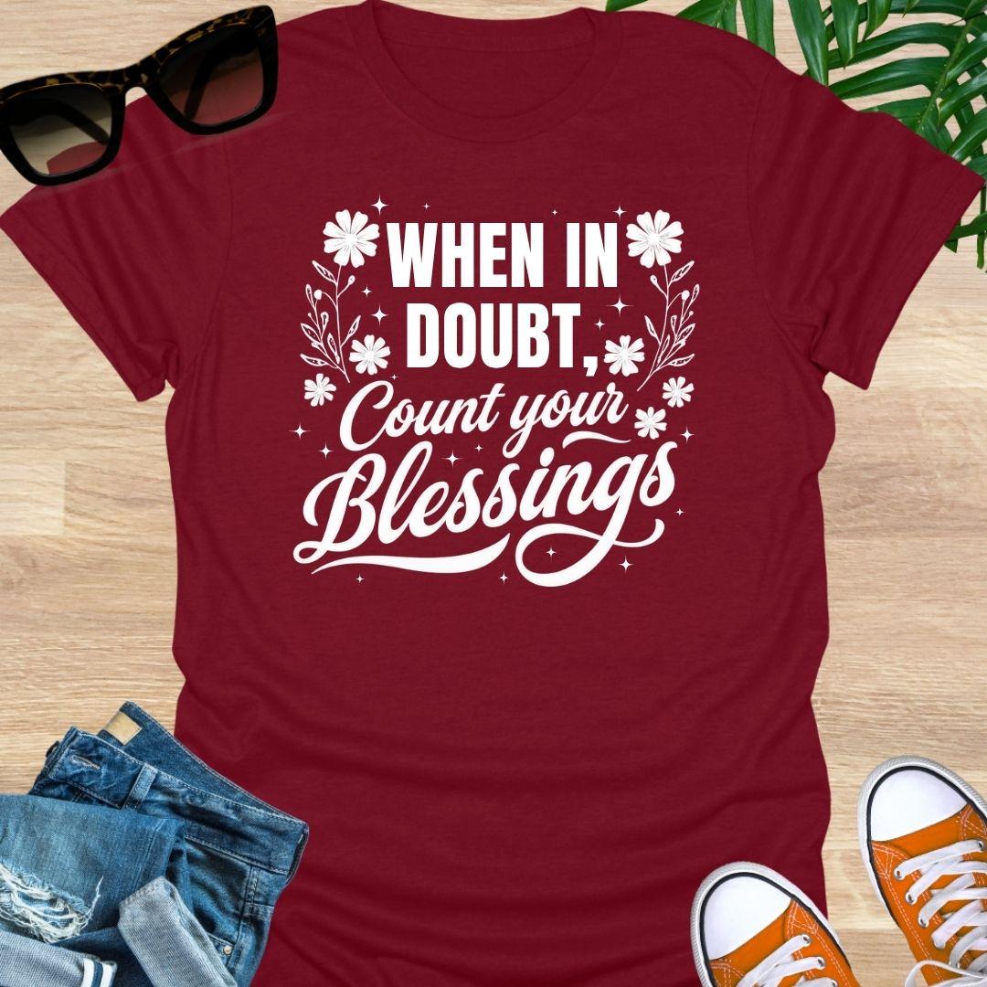“When in Doubt, Count Your Blessings” in white script with floral and sparkle accents on a red unisex tee.