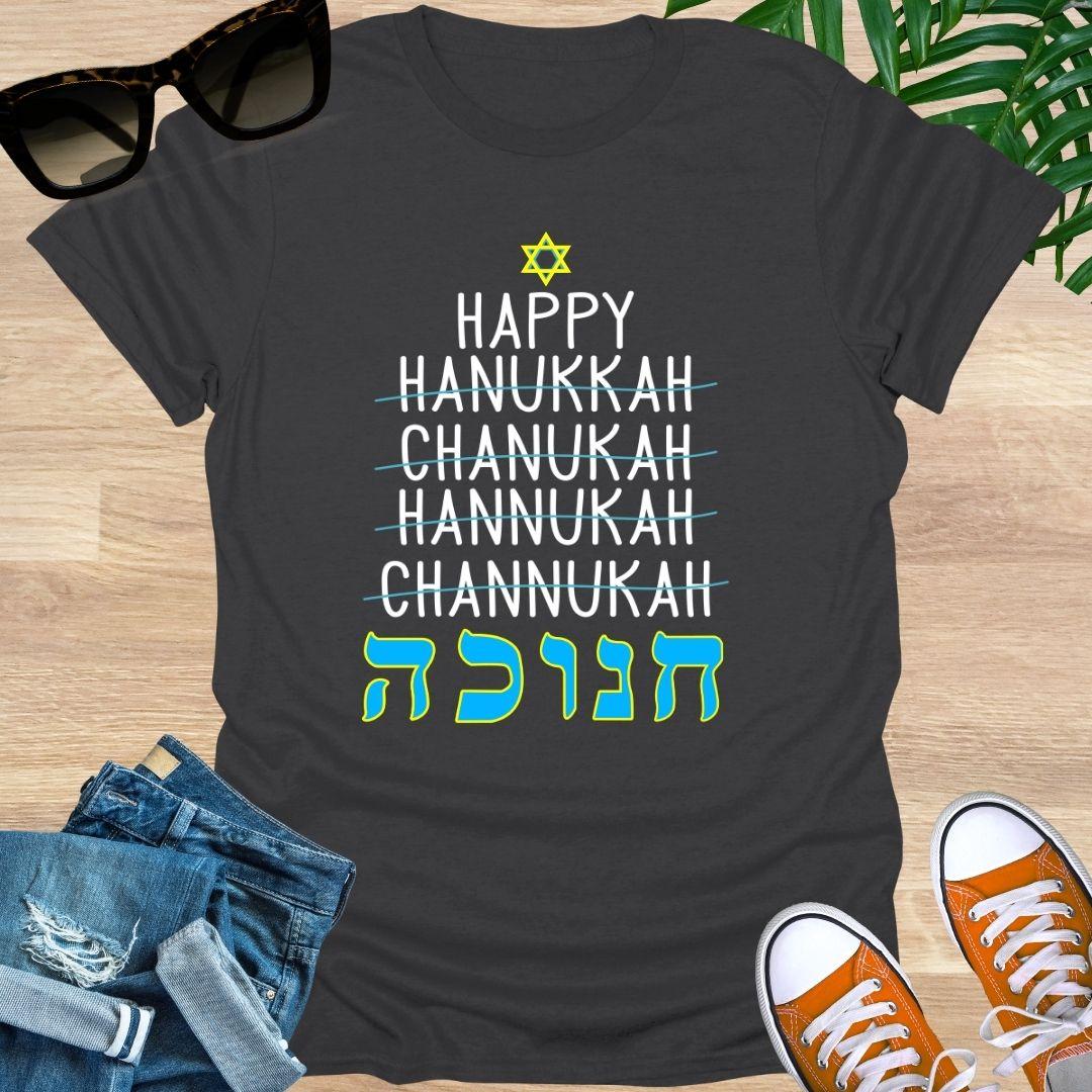 Happy Hanukkah with crossed-out spellings and large Hebrew letters plus a Star of David on a charcoal unisex tee.