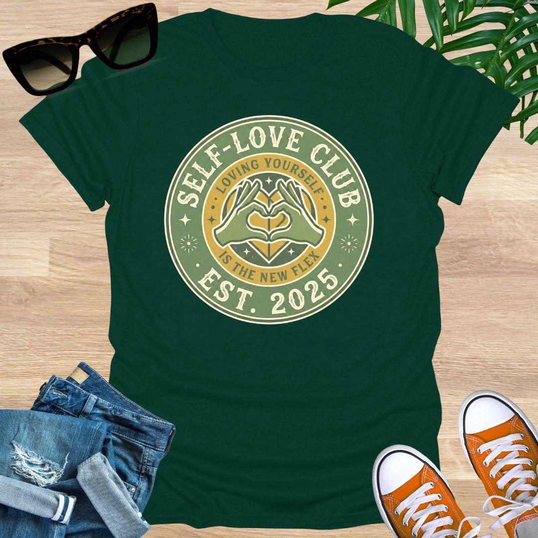 Vintage badge-style design with hands forming a heart and text “Self-Love Club – Loving Yourself Is the New Flex.” on a forest green unisex tee