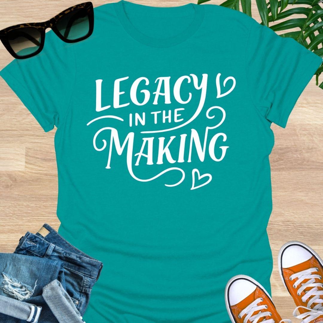 White script “Legacy in the Making” with heart flourishes on a jade dome motivational graphic tee.