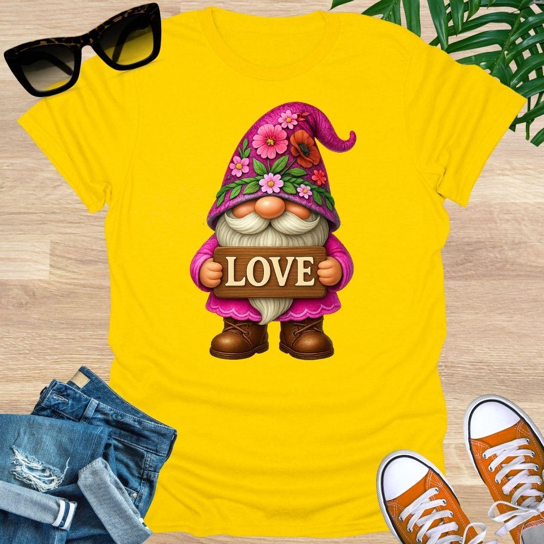 Yellow t-shirt with a gnome holding a 'LOVE' sign, sunglasses, jeans, and shoes on a wooden surface.