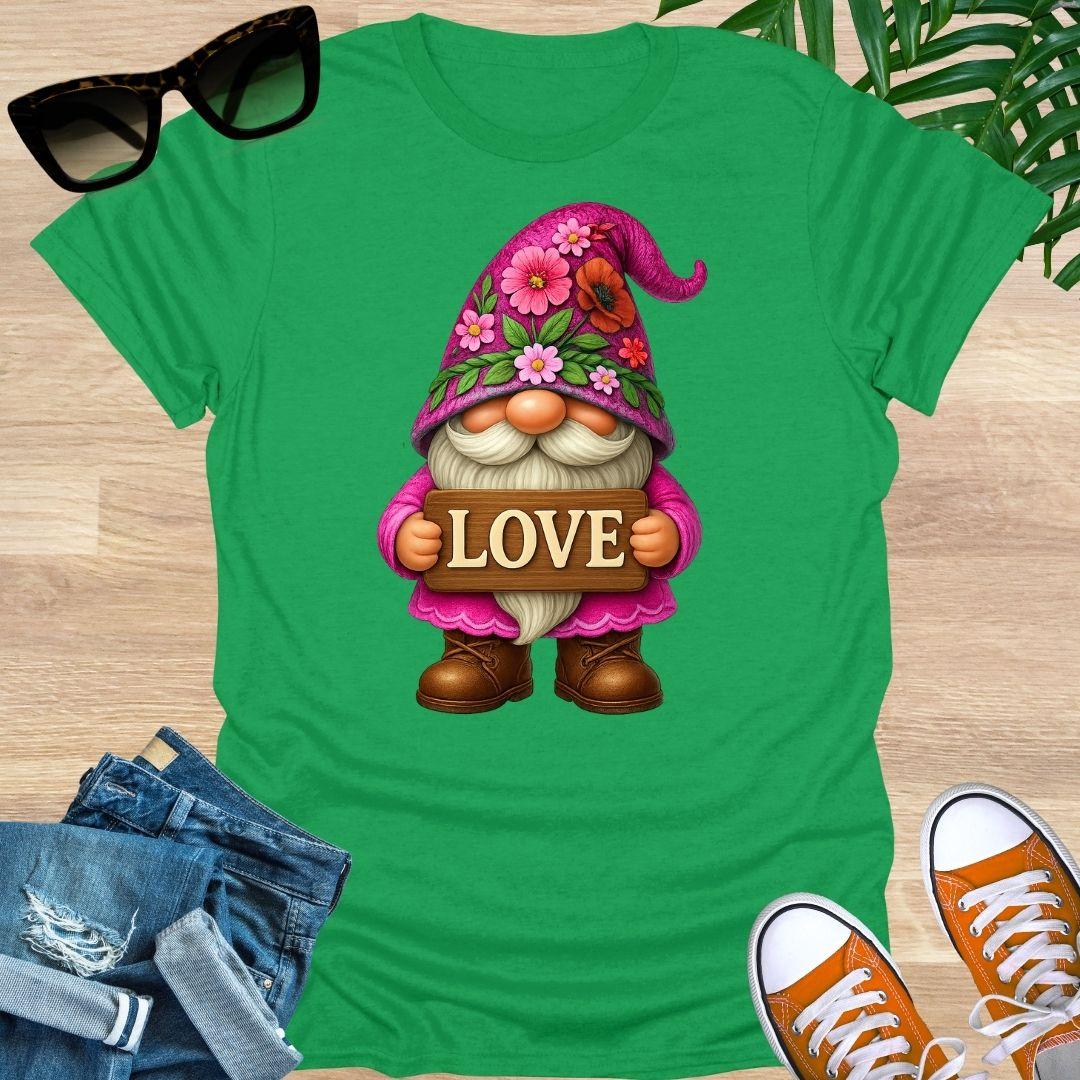Green t-shirt with a gnome holding a 'LOVE' sign, surrounded by jeans and sneakers on a wooden surface.