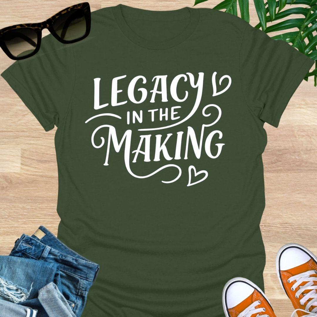 White script “Legacy in the Making” with heart flourishes on a military greenj motivational graphic tee.