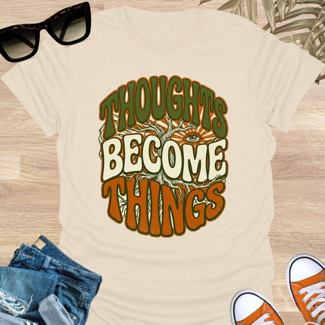 Retro design with tree roots, an eye, and the phrase “Thoughts Become Things” in earthy colors on a beige unisex tee.