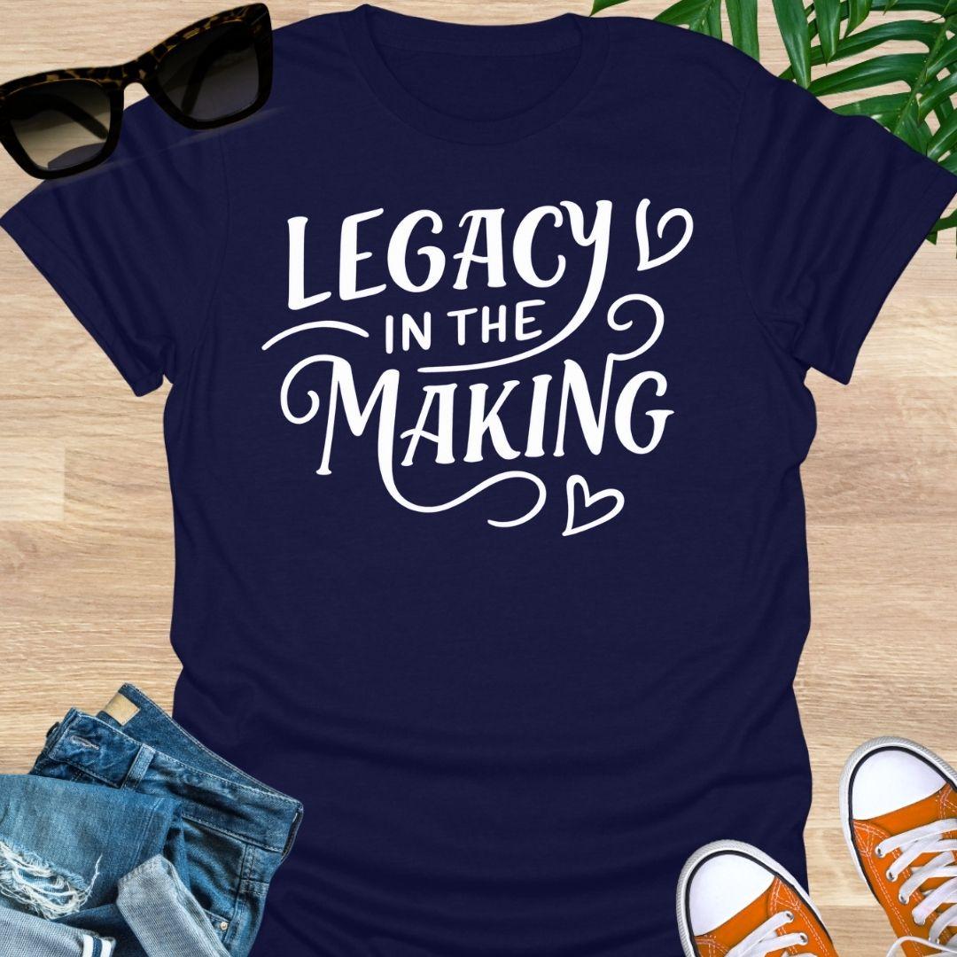 White script “Legacy in the Making” with heart flourishes on a navy motivational graphic tee.