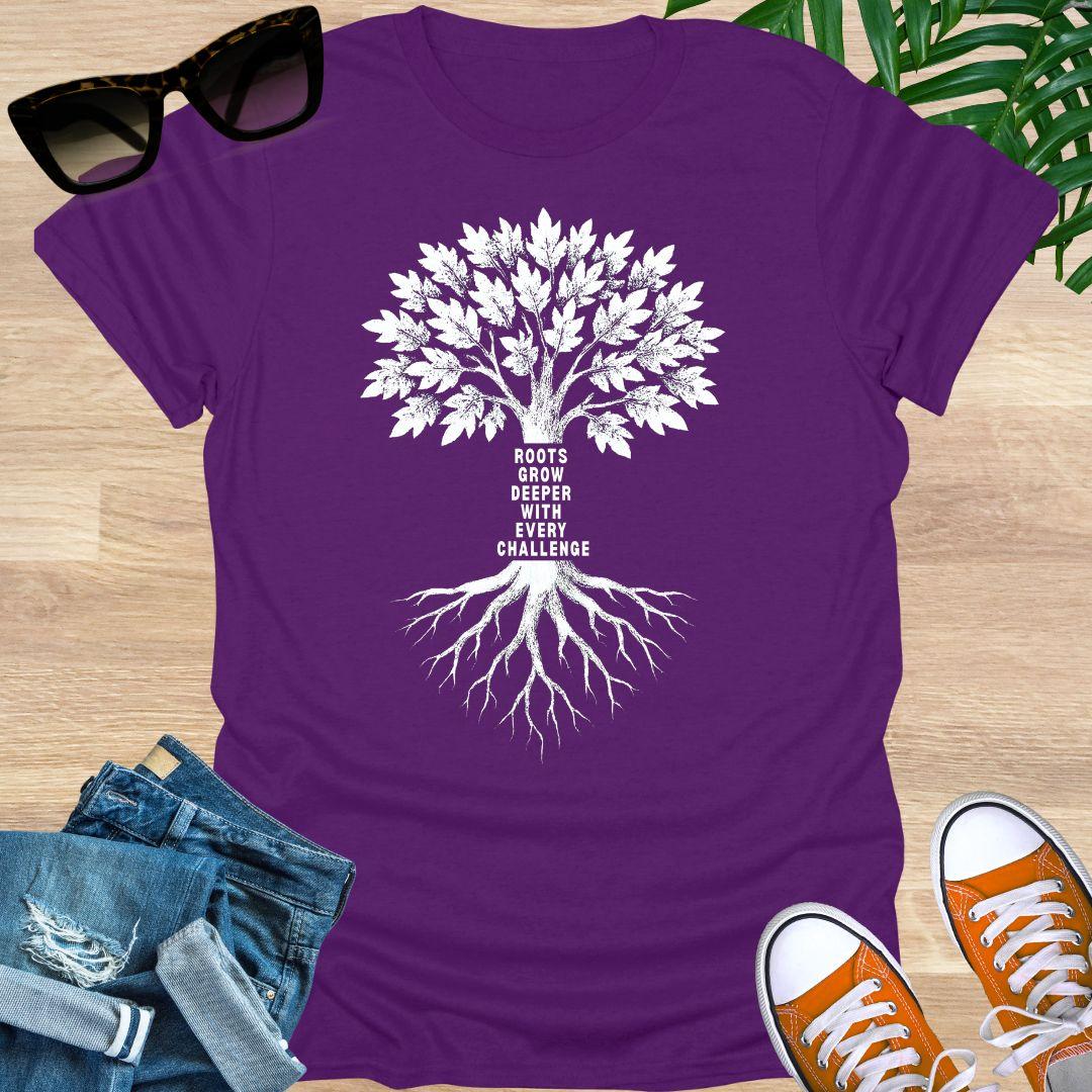 White tree with deep roots and the phrase “Roots grow deeper with every challenge” on a purple unisex tee.