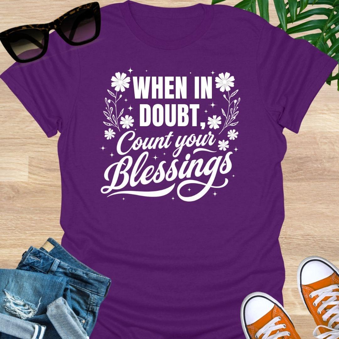 “When in Doubt, Count Your Blessings” in white script with floral and sparkle accents on a purple unisex tee.