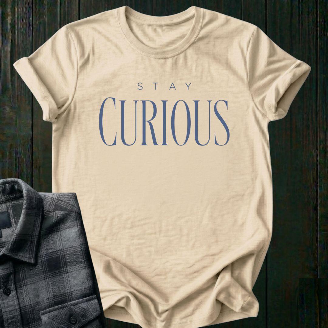 Elegant minimalist typography design featuring the phrase "Stay Curious" in refined serif lettering on a beige tee.