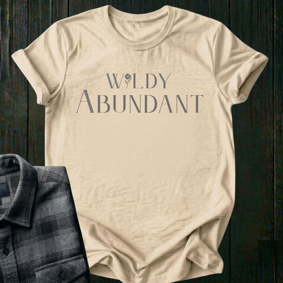 Elegant typography design featuring the phrase "Wildly Abundant" with a flower replacing the letter I in Wildly on a beige tee.