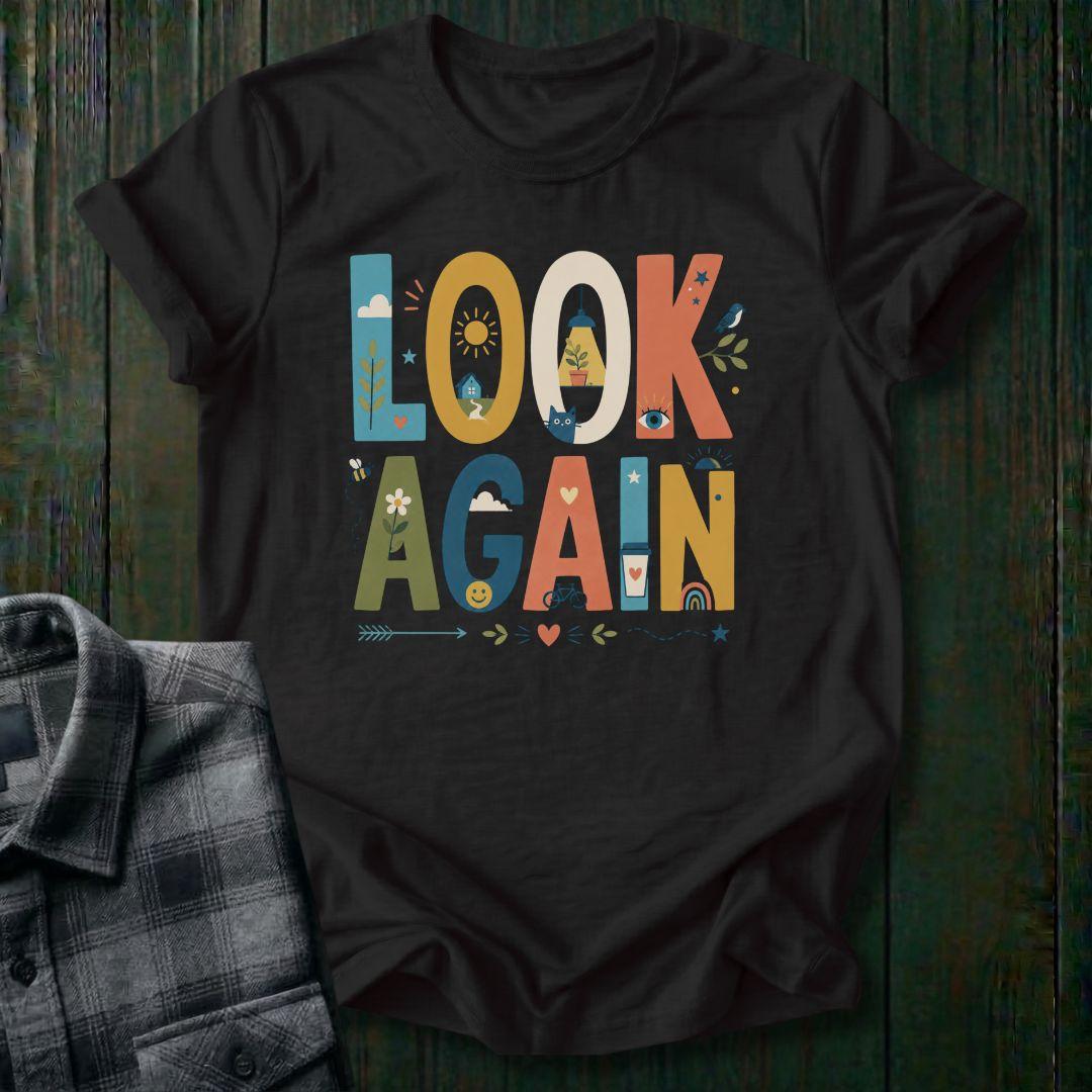 Colorful typography design featuring the phrase "Look Again" filled with cheerful illustrations including a house, sunshine, flowers, coffee cup, bicycle, rainbow, cat, and bird on a black tee