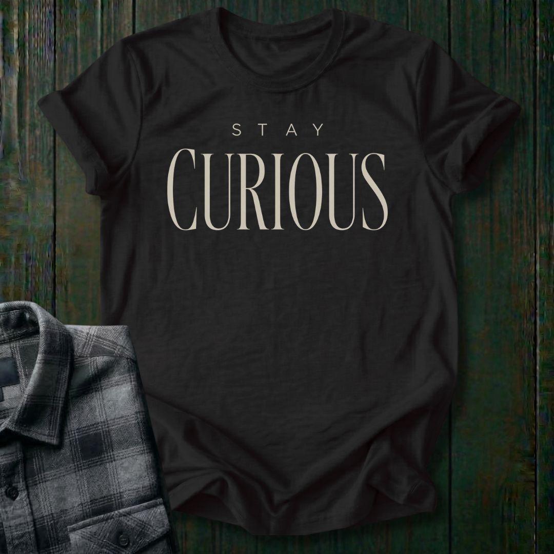 Elegant minimalist typography design featuring the phrase "Stay Curious" in refined serif lettering on a black tee.