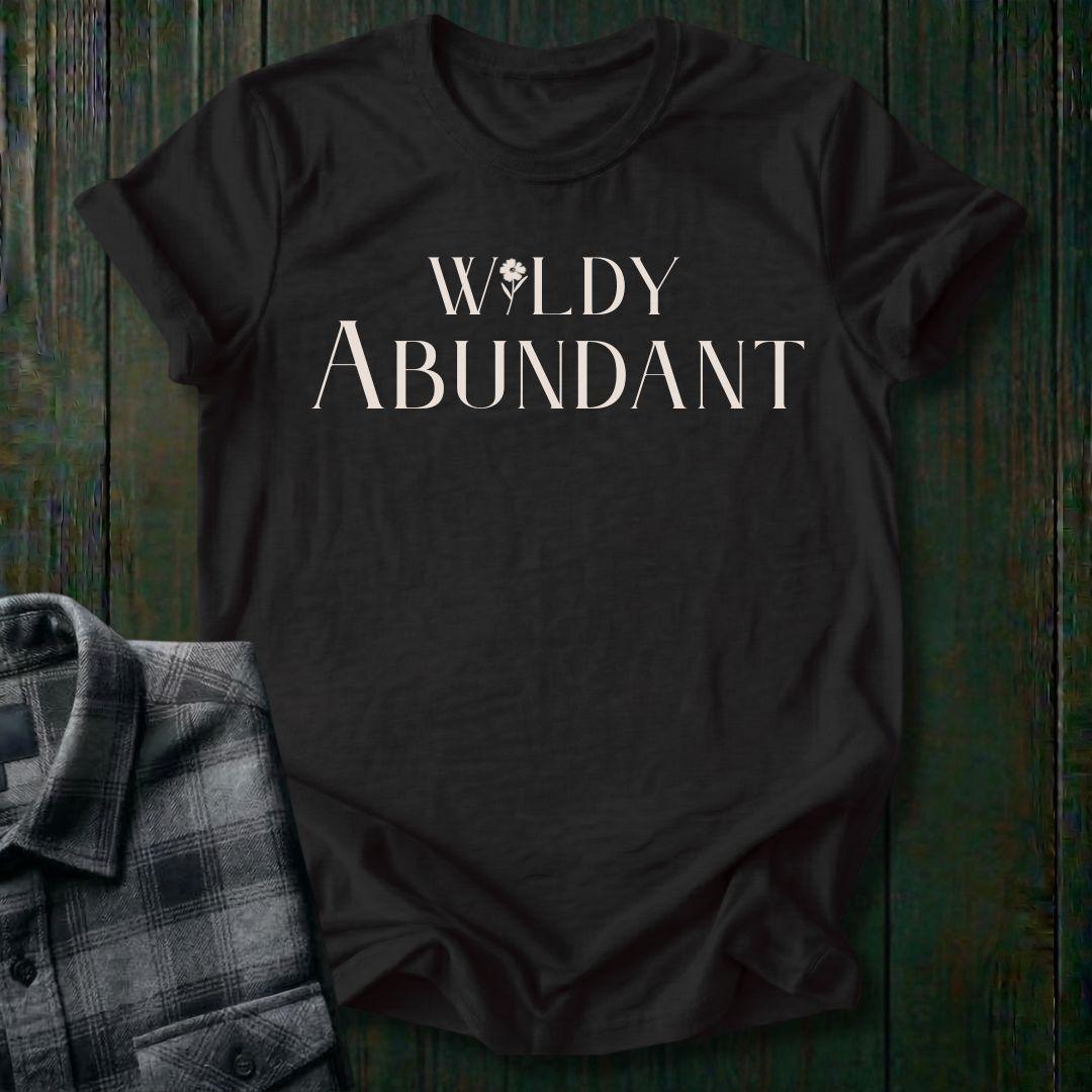 Elegant typography design featuring the phrase "Wildly Abundant" with a flower replacing the letter I in Wildly on a black tee.