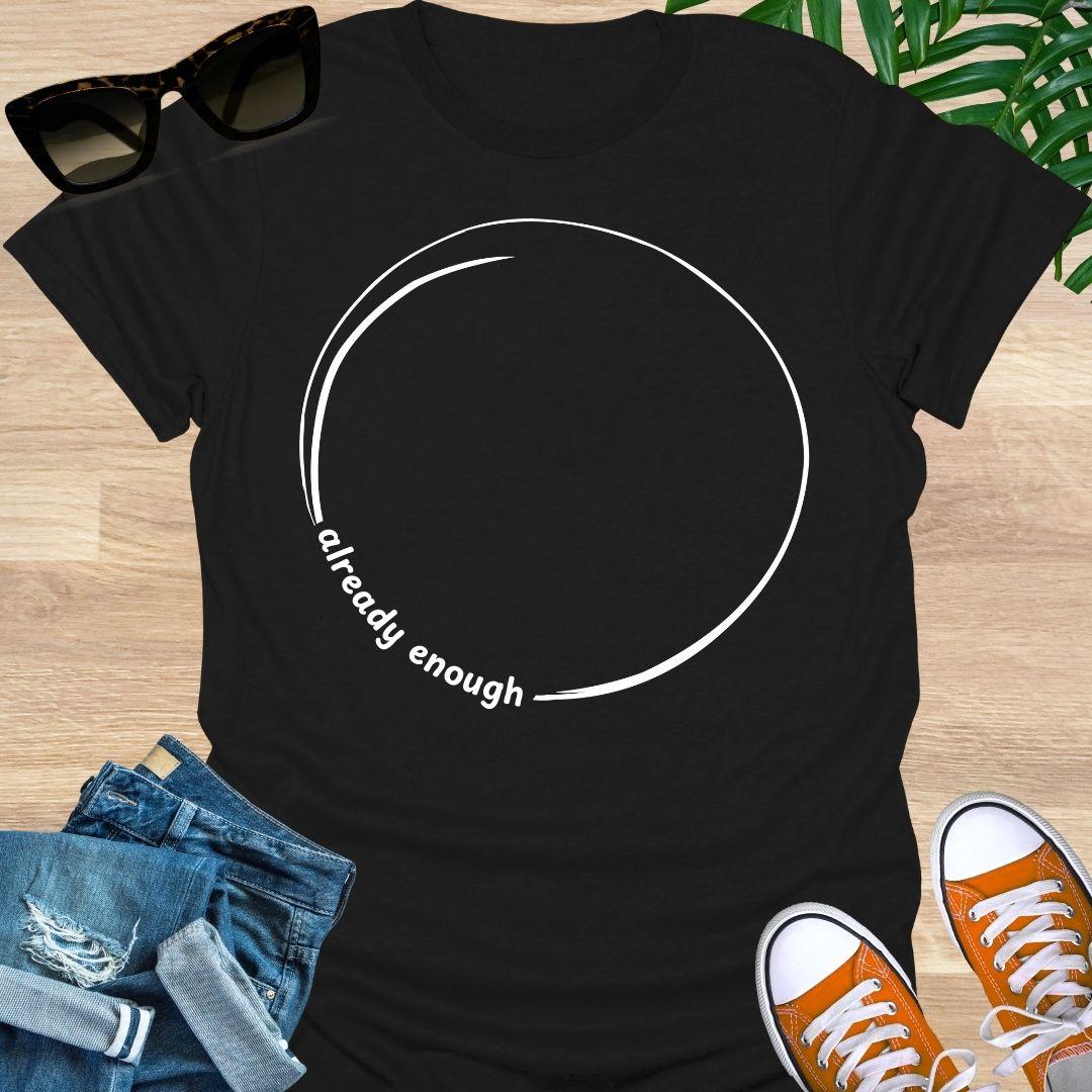 Minimal incomplete circle line art with the words “already enough” on a black unisex t-shirt