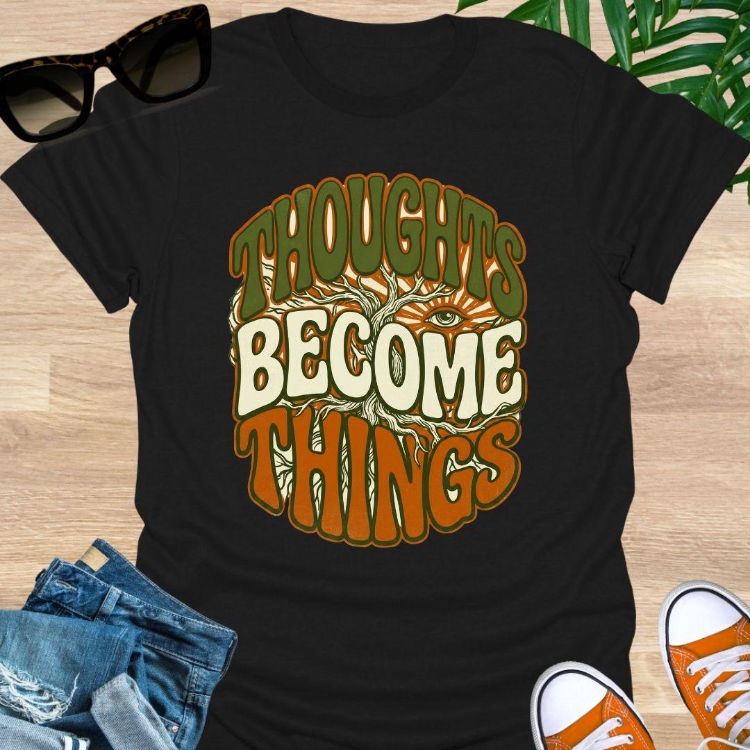 Retro design with tree roots, an eye, and the phrase “Thoughts Become Things” in earthy colors on a black unisex tee.