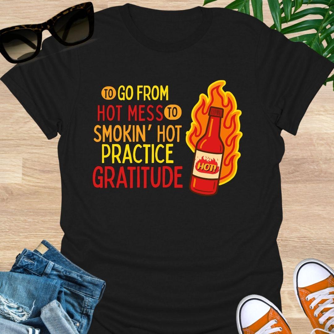 Flaming hot sauce bottle beside the text “Hot Mess to Smokin’ Hot, Practice Gratitude” on a black unisex tee.