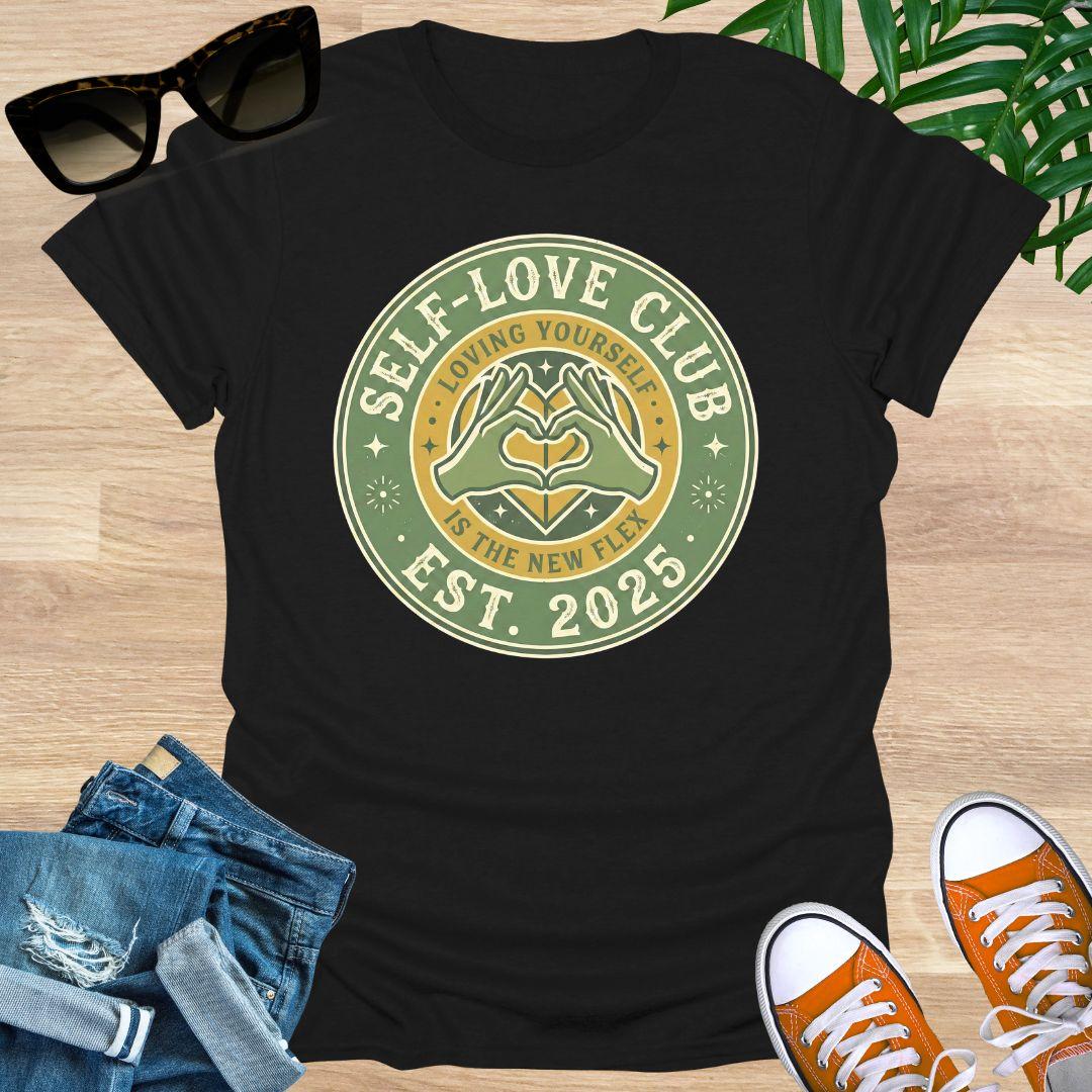 Vintage badge-style design with hands forming a heart and text “Self-Love Club – Loving Yourself Is the New Flex.” on a black unisex tee