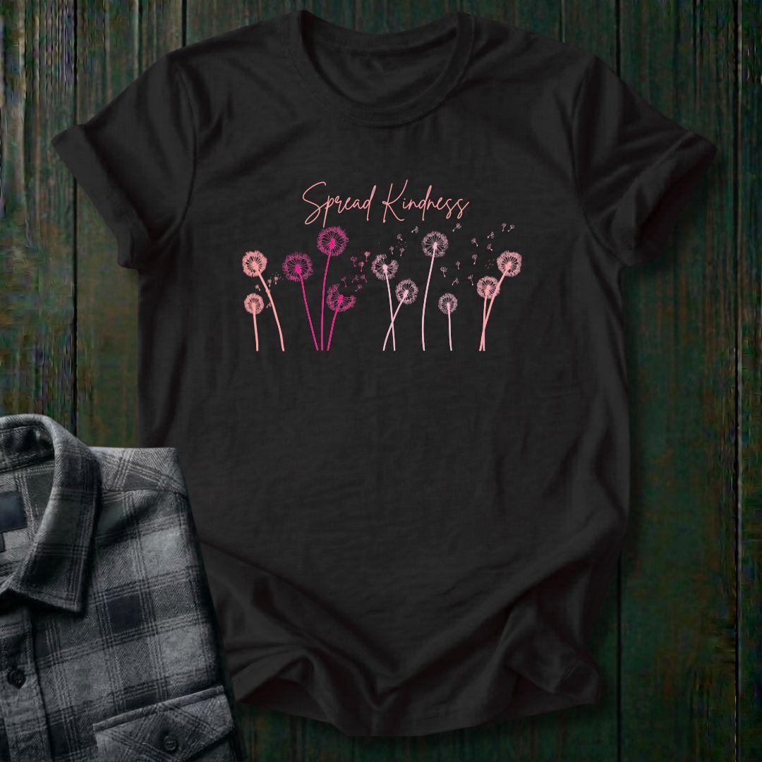 Black t-shirt with 'Spread Kindness' text and dandelion graphics on a wooden surface.