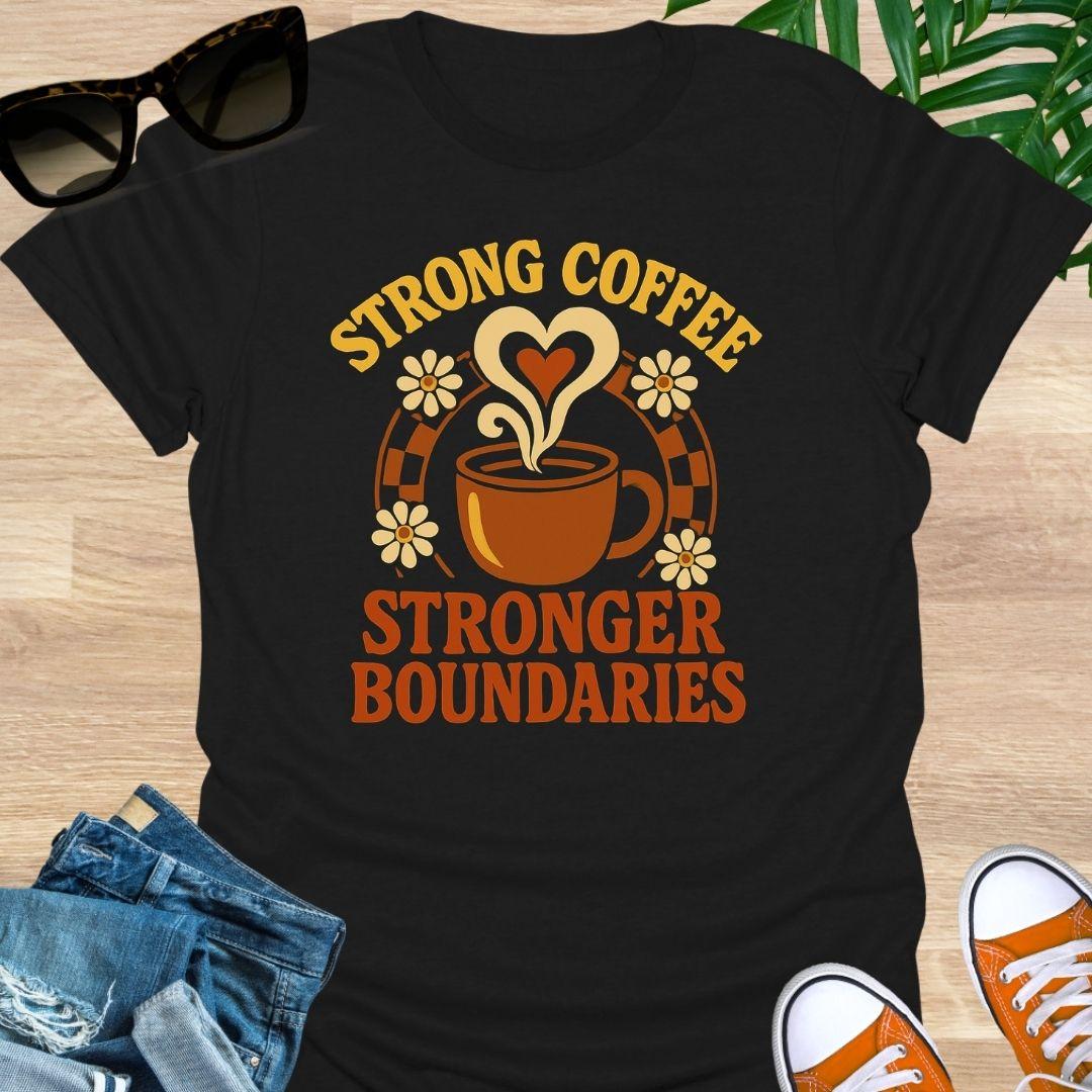 Black unisex t-shirt. Retro coffee cup with heart-shaped steam and daisies over the words Strong Coffee Stronger Boundaries 