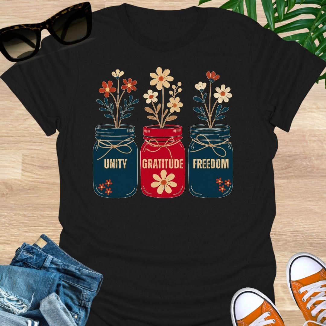 Three mason jars labeled Unity, Gratitude, Freedom with wildflowers in Americana colors on a black unisex graphic tee.