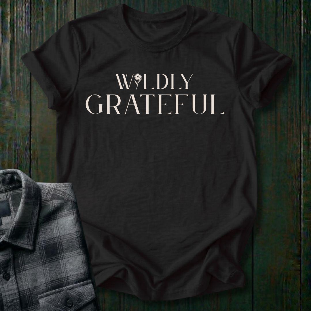Elegant typography design featuring the phrase "Wildly Grateful" with a flower replacing the letter I in Wildly on a black tee