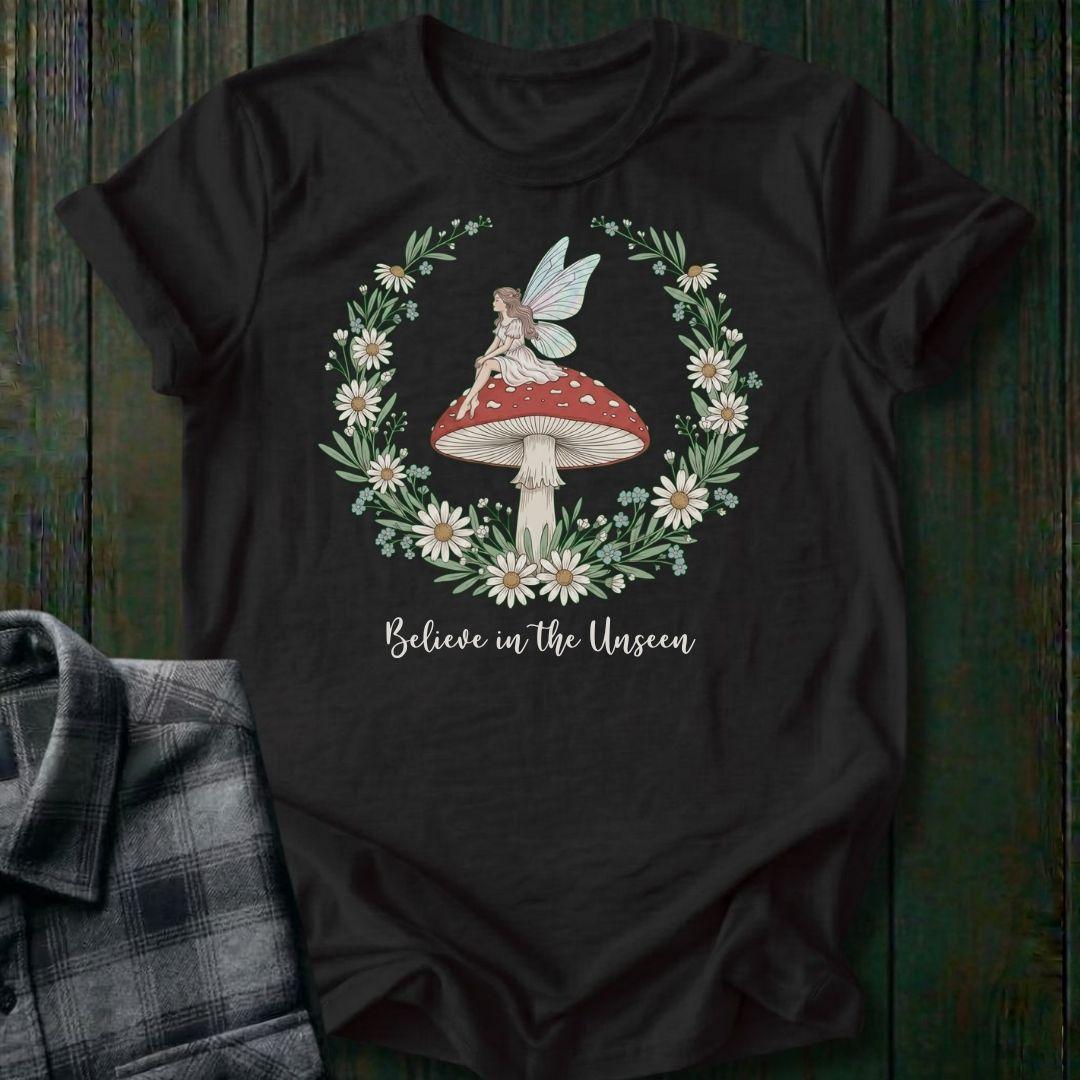 Black t-shirt with fairy and mushroom design on a wooden surface