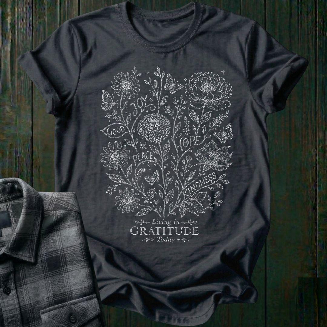 Vintage botanical illustration featuring flowers, butterflies, leaves, and the inspirational words joy, hope, peace, kindness, and good above the phrase Living in Gratitude Today on a charcoal shirt