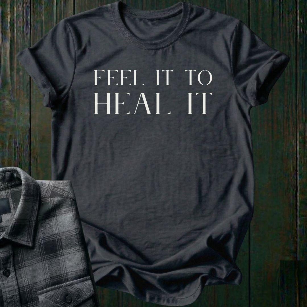 Minimalist typography design featuring the phrase "Feel It to Heal It" in elegant serif lettering on a charcoal tee.