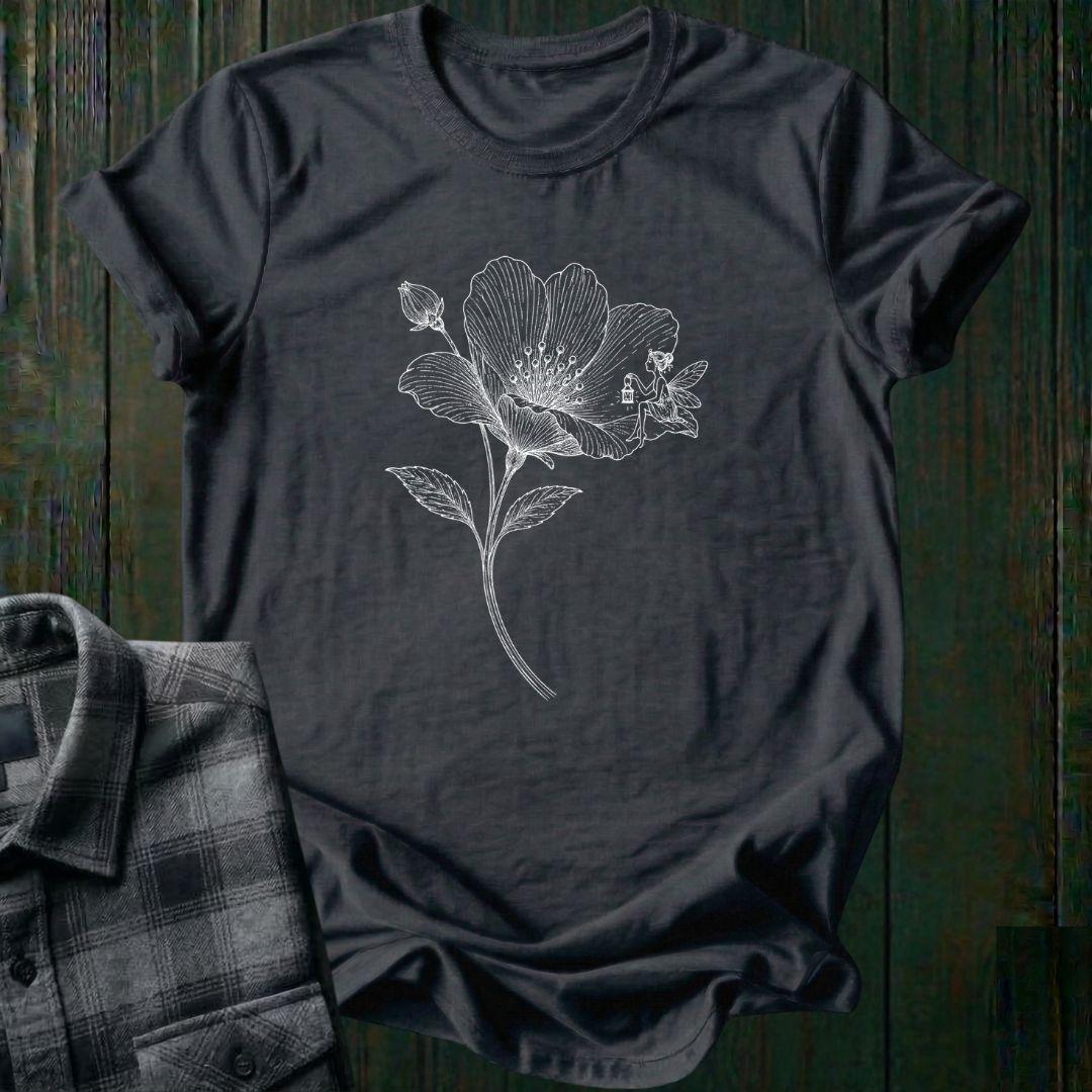 Vintage botanical illustration of a blooming wildflower with a tiny fairy sitting on one petal, surrounded by delicate engraved details and a flower bud on a charcoal tee.