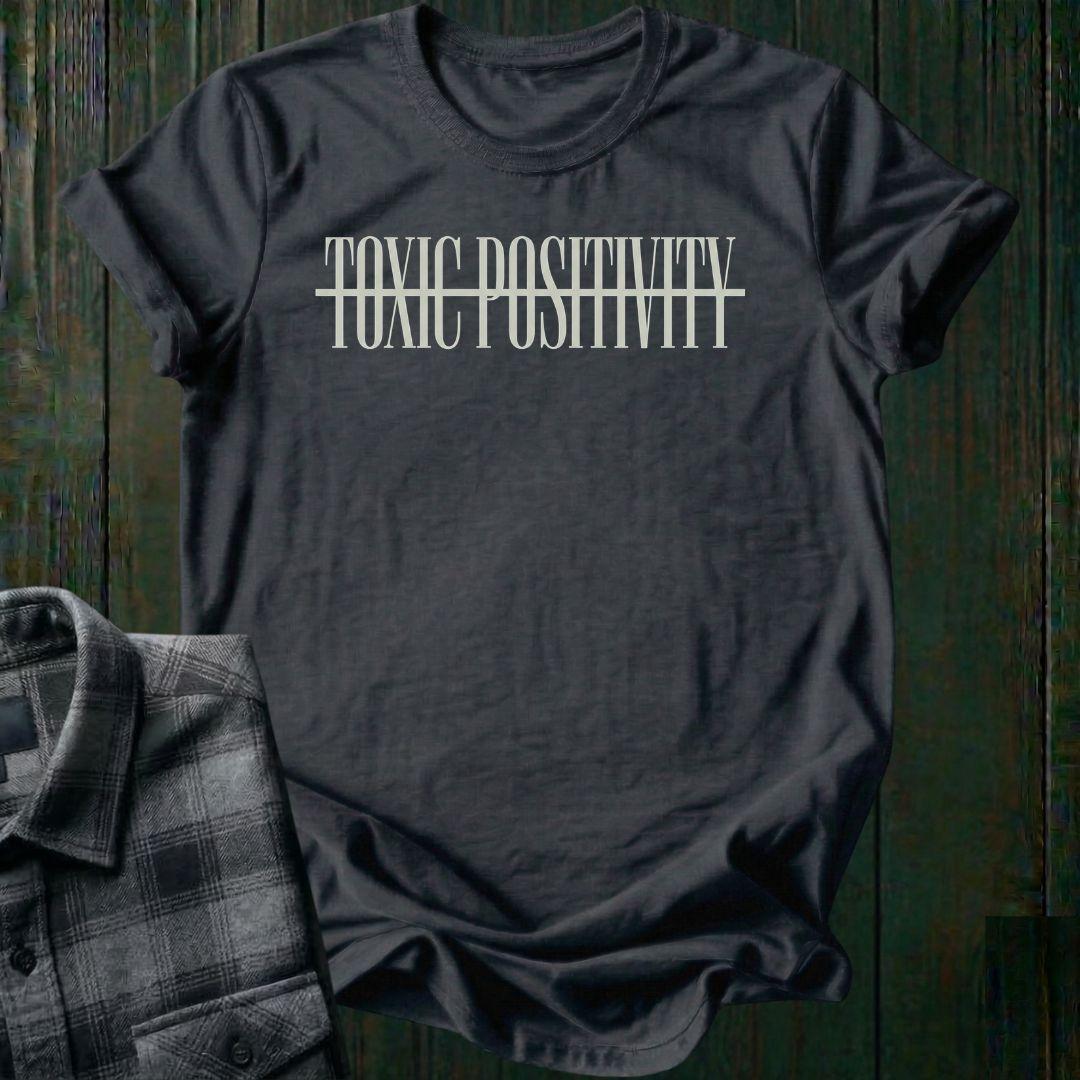 Charcoal tee with minimalist typography design featuring the phrase "No More Toxic Positivity" in bold modern lettering with a horizontal line running through the center of the text.