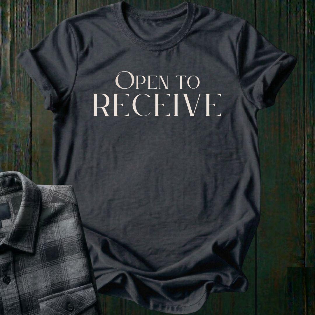 Elegant minimalist typography design featuring the phrase "Open to Receive" in refined serif lettering on a charcoal tee