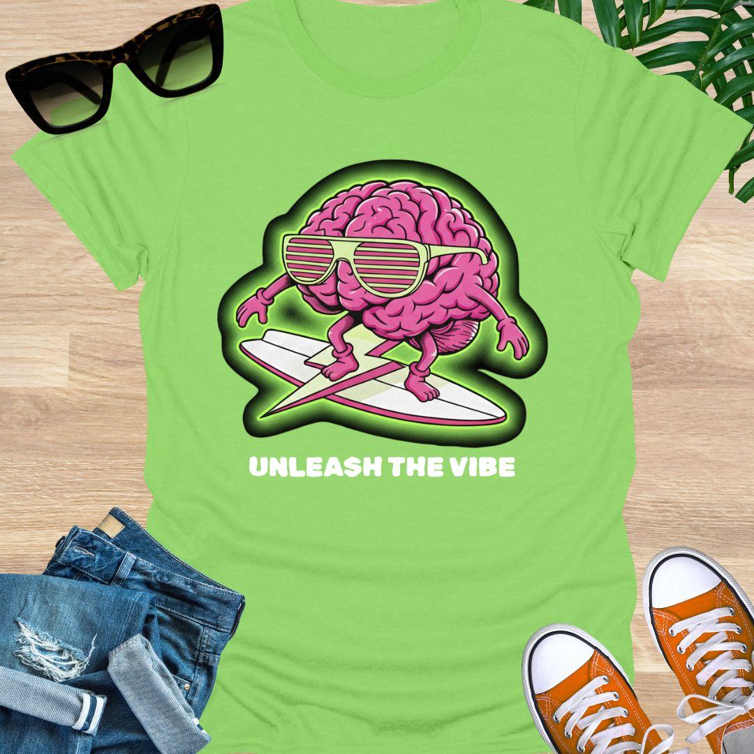 Pink cartoon brain wearing sunglasses surfing on a board with green glow and the words “Unleash the Vibe” on a lime green t-shirt
