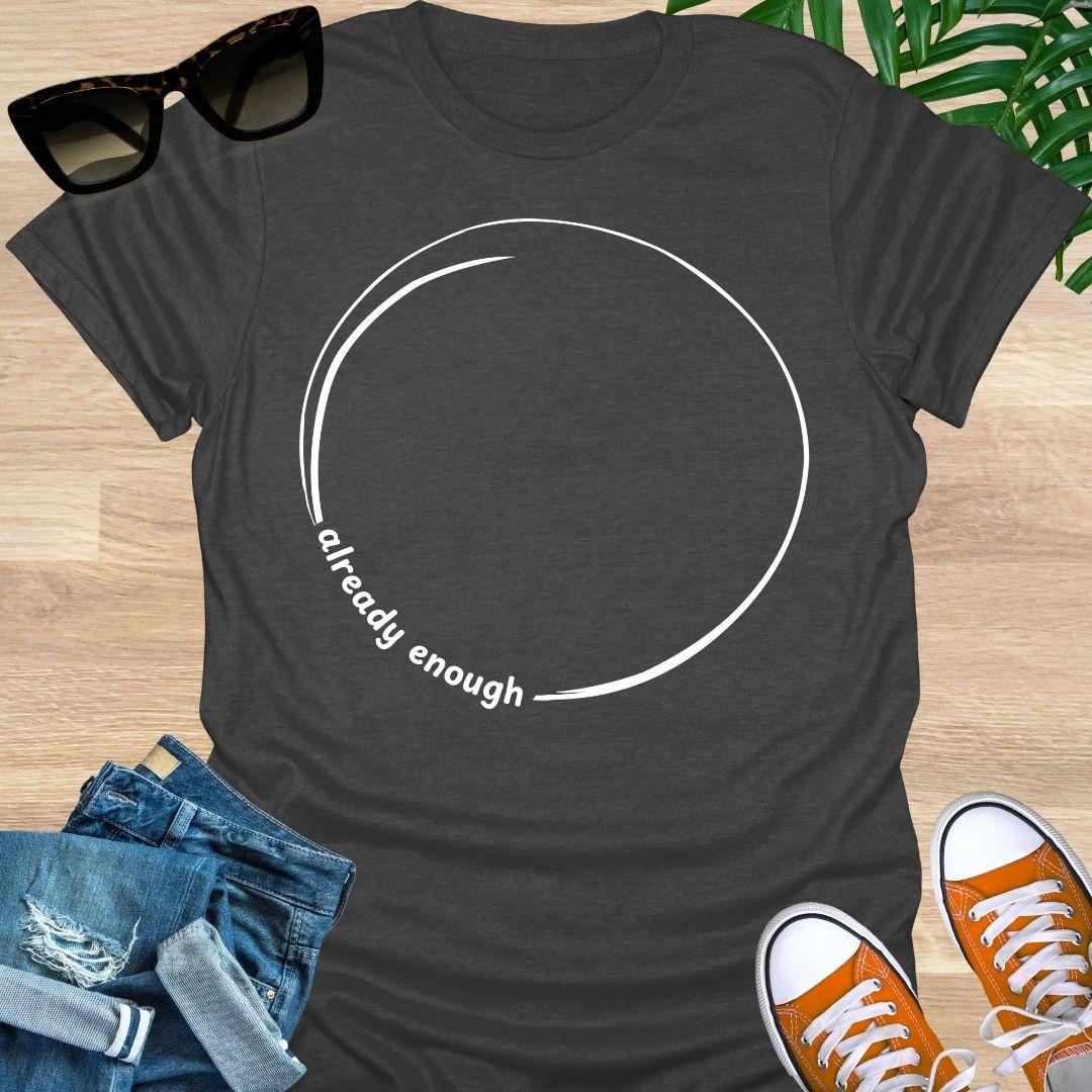 Minimal incomplete circle line art with the words “already enough” on a heather gray unisex t-shirt
