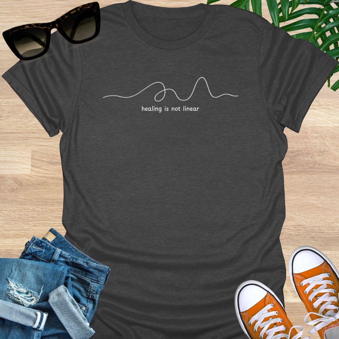 Heather Gray unisex t-shirt with minimalist line art and white text reading healing is not linear