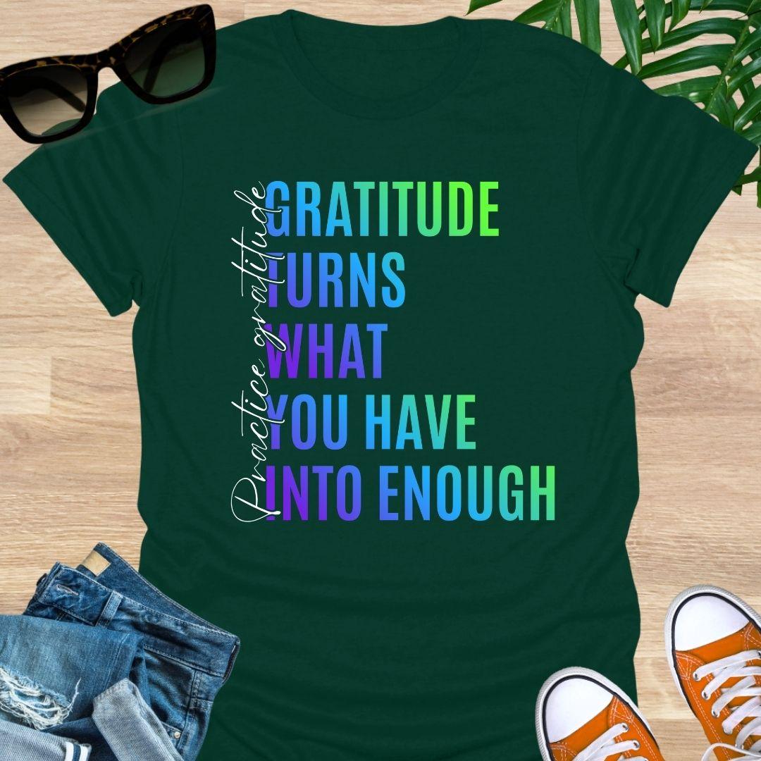 Gradient text tee reading “Gratitude turns what you have into enough” with script “practice gratitude" on a forest green unisex tee