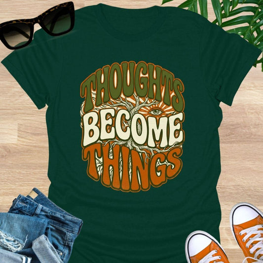 Retro design with tree roots, an eye, and the phrase “Thoughts Become Things” in earthy colors on a forest green unisex tee.