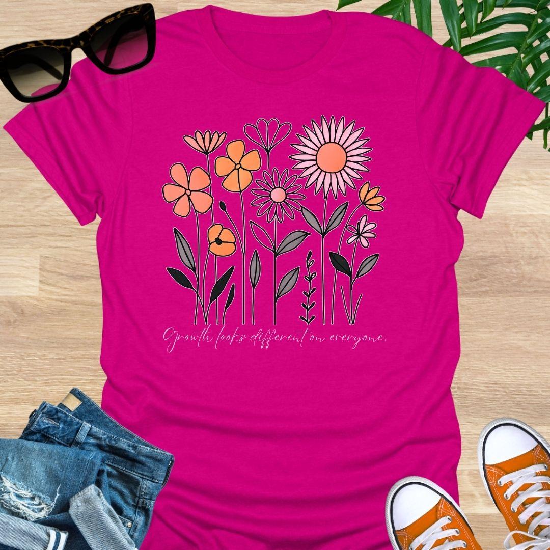 Hot Pink unisex t-shirt. Hand-drawn wildflowers with the script “Growth looks different on everyone” 