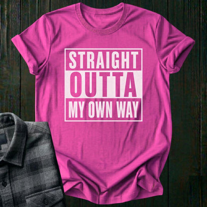 Pink t-shirt with 'Straight Outta My Own Way' text on a wooden surface