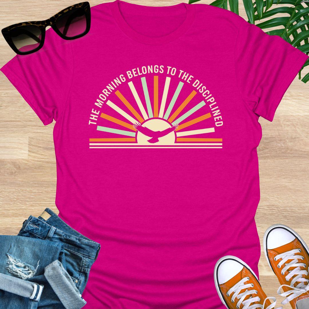 Sunrise with eagle silhouette and Morning Belongs to the Disciplined message symbolizing discipline, focus, growth, and success mindset on a hot pink tee