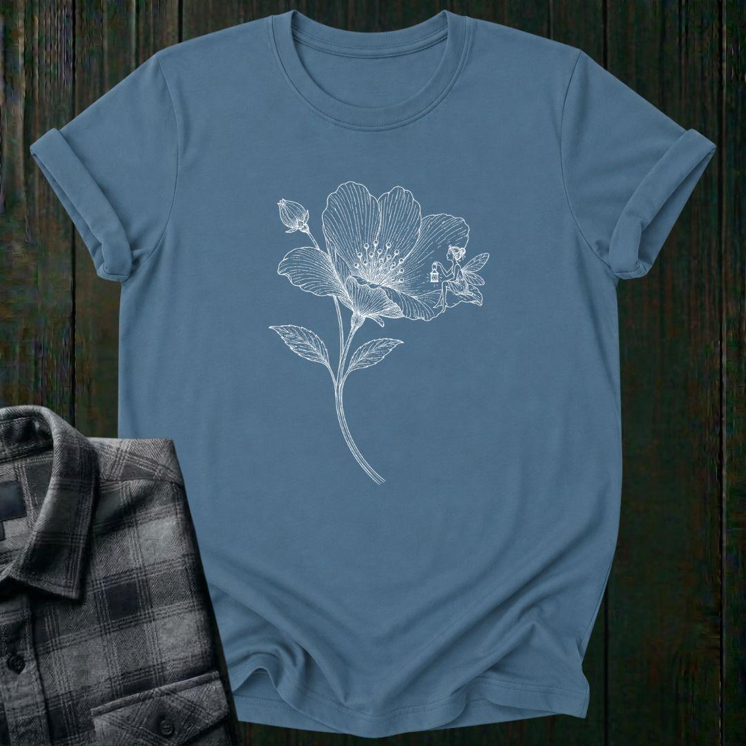 Vintage botanical illustration of a blooming wildflower with a tiny fairy sitting on one petal, surrounded by delicate engraved details and a flower bud on a indigo blue tee.