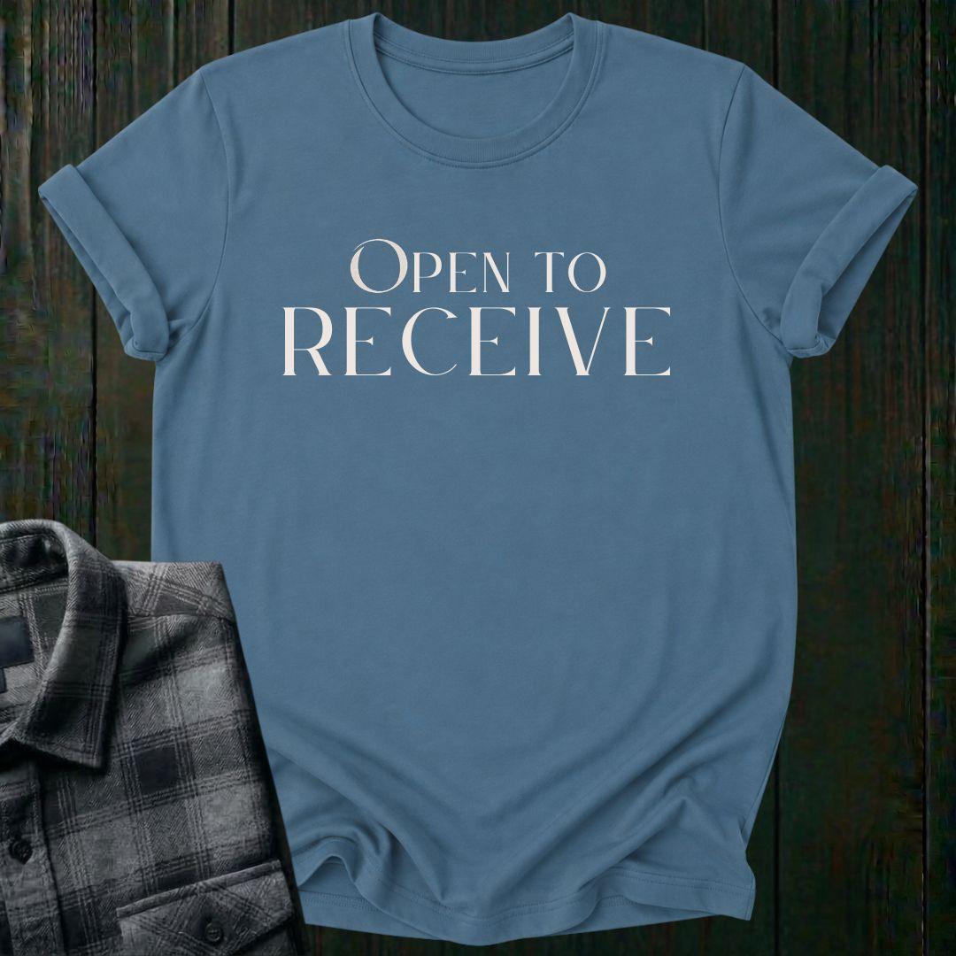 Elegant minimalist typography design featuring the phrase "Open to Receive" in refined serif lettering on an indigo blue tee