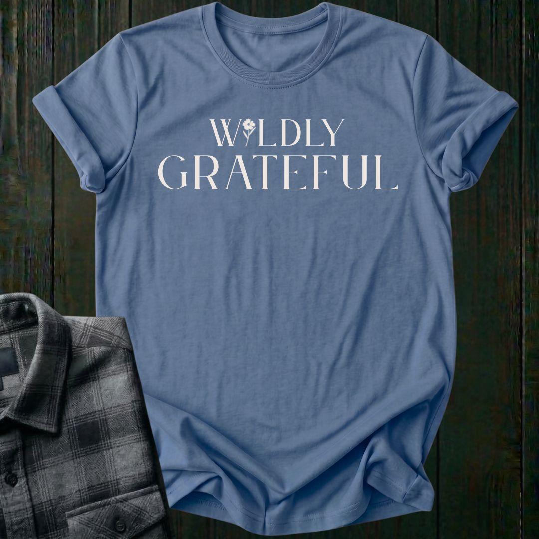 Elegant typography design featuring the phrase "Wildly Grateful" with a flower replacing the letter I in Wildly on an indigo blue tee