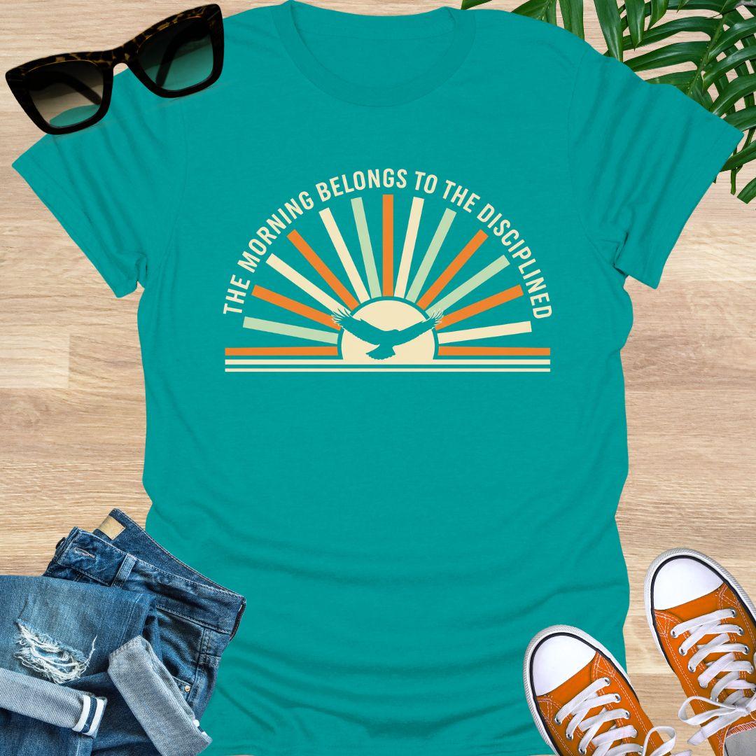 Sunrise with eagle silhouette and Morning Belongs to the Disciplined message symbolizing discipline, focus, growth, and success mindset on a jade dome tee